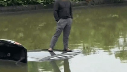 “淡定哥”驾车冲入鱼塘，双手插兜等救援